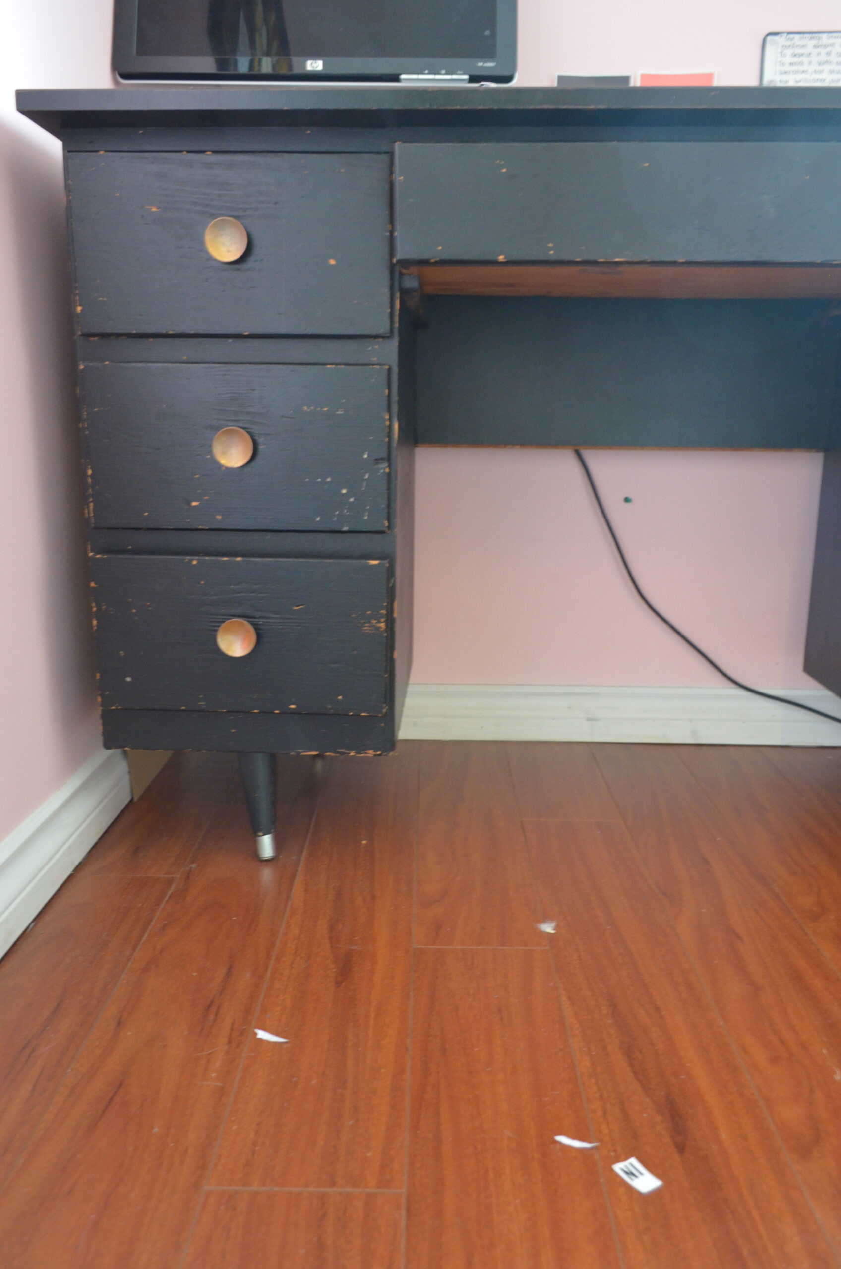 Photo of the author's old wooden desk, painted black, with brass drawer handles.