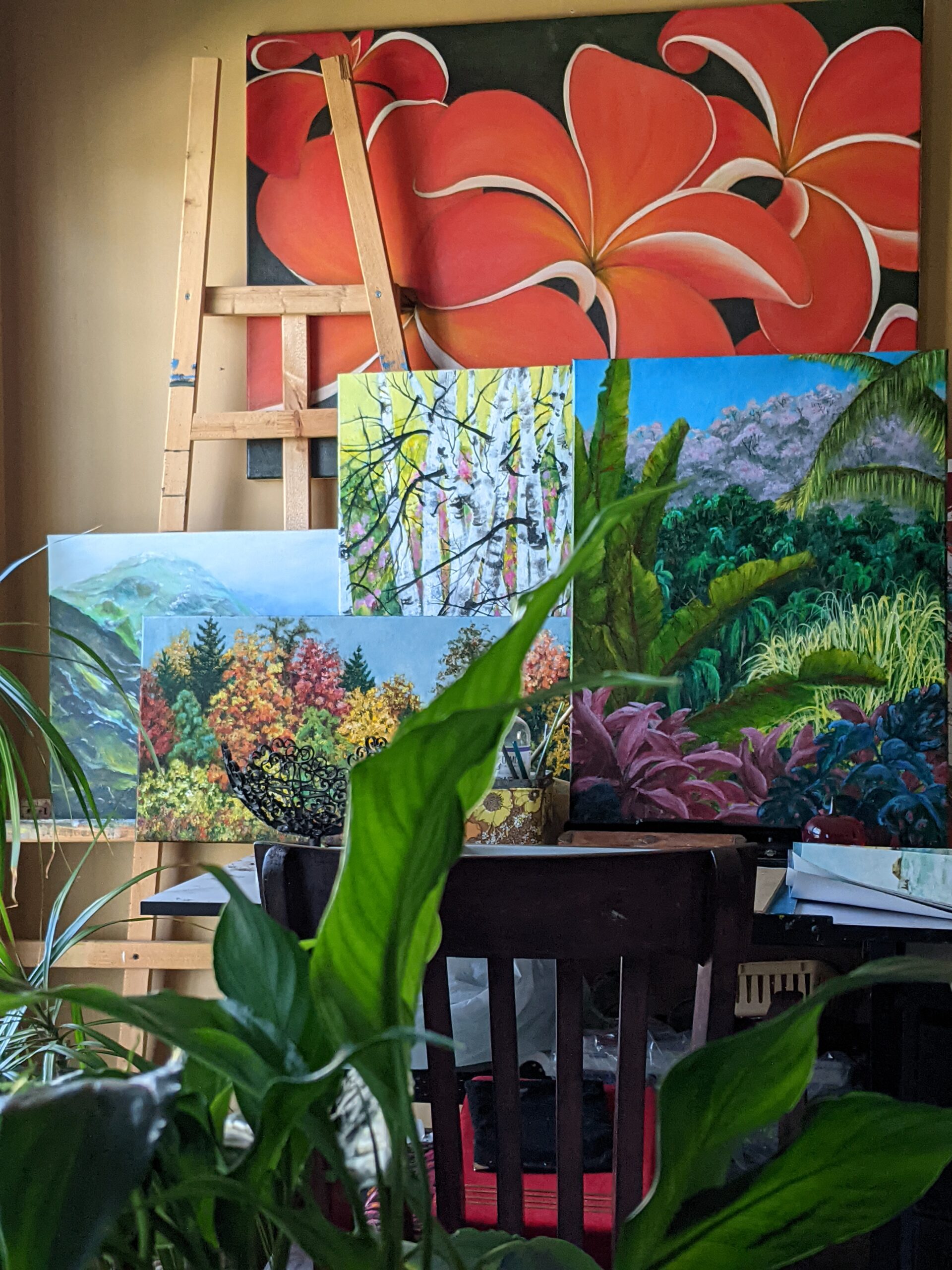 Photo of the author's painting easel, with multiple paintings of foliage resting on and around the easel.