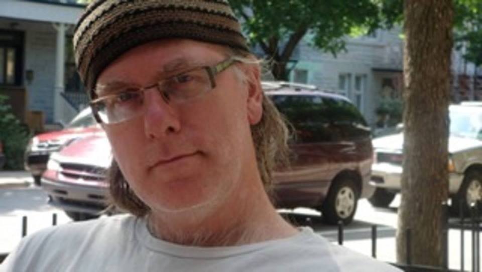 Photo of the author, Mark Foss. He is wearing a brown striped hat and a pair of glasses.